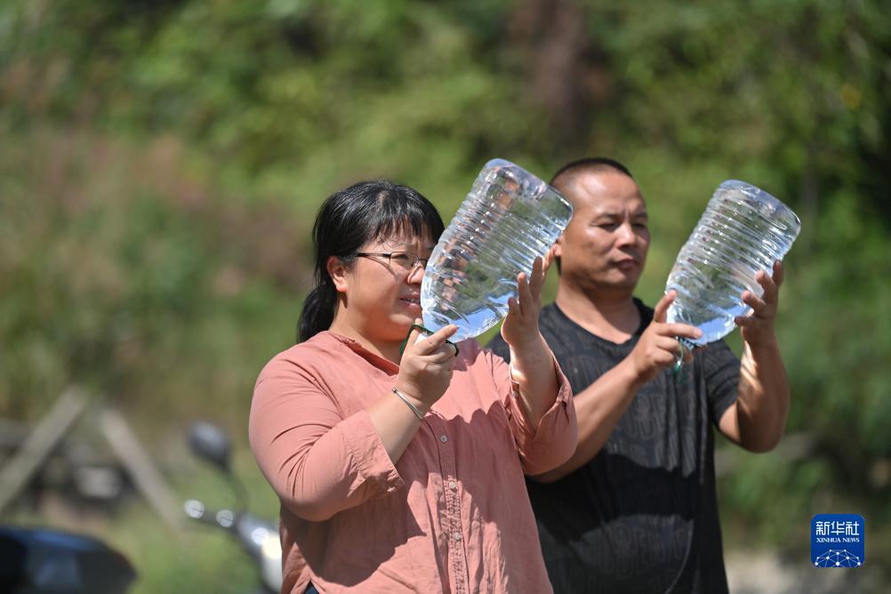 楊寧（左）在查看村民剛剛采集的水樣，為山泉水引水工程做準備（10月8日攝）。新華社記者 黃孝邦 攝